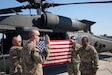 Soldiers in front of helicopter with flag