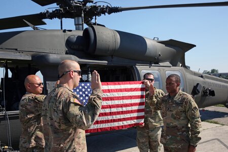 Soldiers in front of helicopter with flag