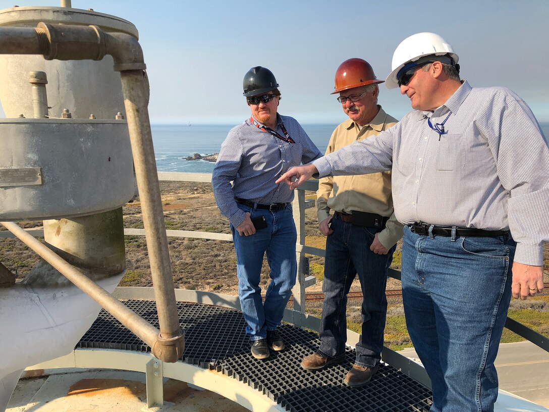 Mike Miller (left) and Dan Lerma (right) from the DLA Energy Aerospace Energy Customer Operations team, along with a vendor, stand on top of the giant liquid nitrogen tank during a tour of the Gaseous Nitrogen Plant on Vandenberg Air Force Base, California. The nitrogen is converted from liquid to gas on site and pushed through a pipeline to the different space-launch complexes on the base.