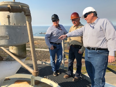 Mike Miller (left) and Dan Lerma (right) from the DLA Energy Aerospace Energy Customer Operations team, along with a vendor, stand on top of the giant liquid nitrogen tank during a tour of the Gaseous Nitrogen Plant on Vandenberg Air Force Base, California. The nitrogen is converted from liquid to gas on site and pushed through a pipeline to the different space-launch complexes on the base.
