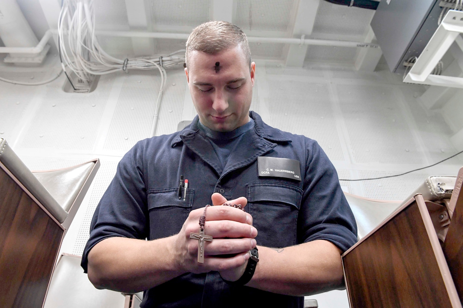 Damage Controlman Fireman Christopher Hauerrberg, from Chicago, prays during an Ash Wednesday service aboard Arleigh Burke-class guided-missile destroyer USS Wayne E. Meyer.