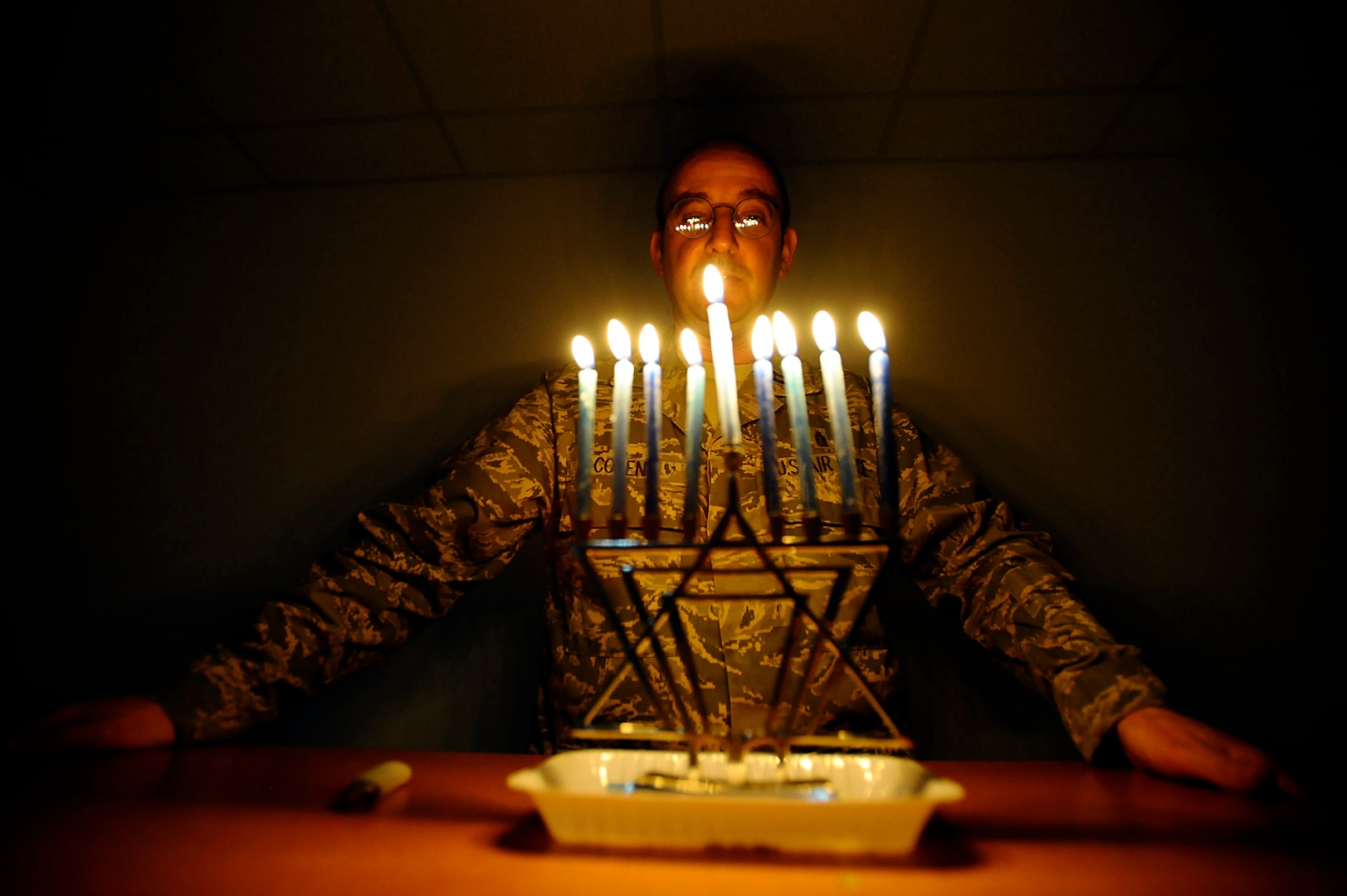 Air Force Capt. Andrew Cohen, chaplain, stands behind a lit menorah during the eighth night of Hanukkah at Joint Base Balad, Iraq. Jewish military chaplains receive a full range of religious supplies from DLA