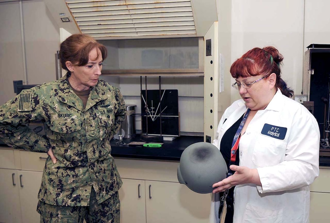 DLA Land and Maritime Commander Navy Rear Adm. Michelle Skubic discusses the results of blunt-force-impact testing for helmets with DLA lab technician Sally Schuster during a visit to Mechanicsburg, Pennsylvania.