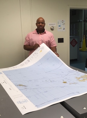 Aaron Ford, DMS employee in the Norfolk mapping facility, holds up a freshly printed map.