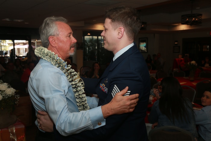 Father in civilian clothes and son in Air Force uniform embrace.