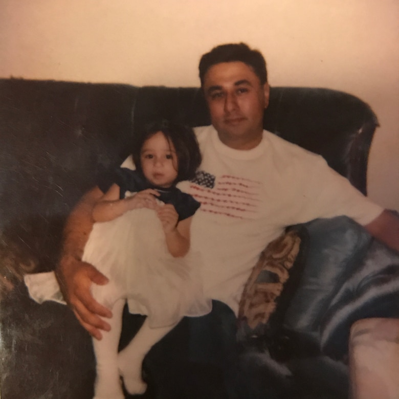 Melissa Cerna, then three years old, and now-retired Air Force Master Sgt. Jose Cerna, her father, sit on a couch in Abilene, Texas.