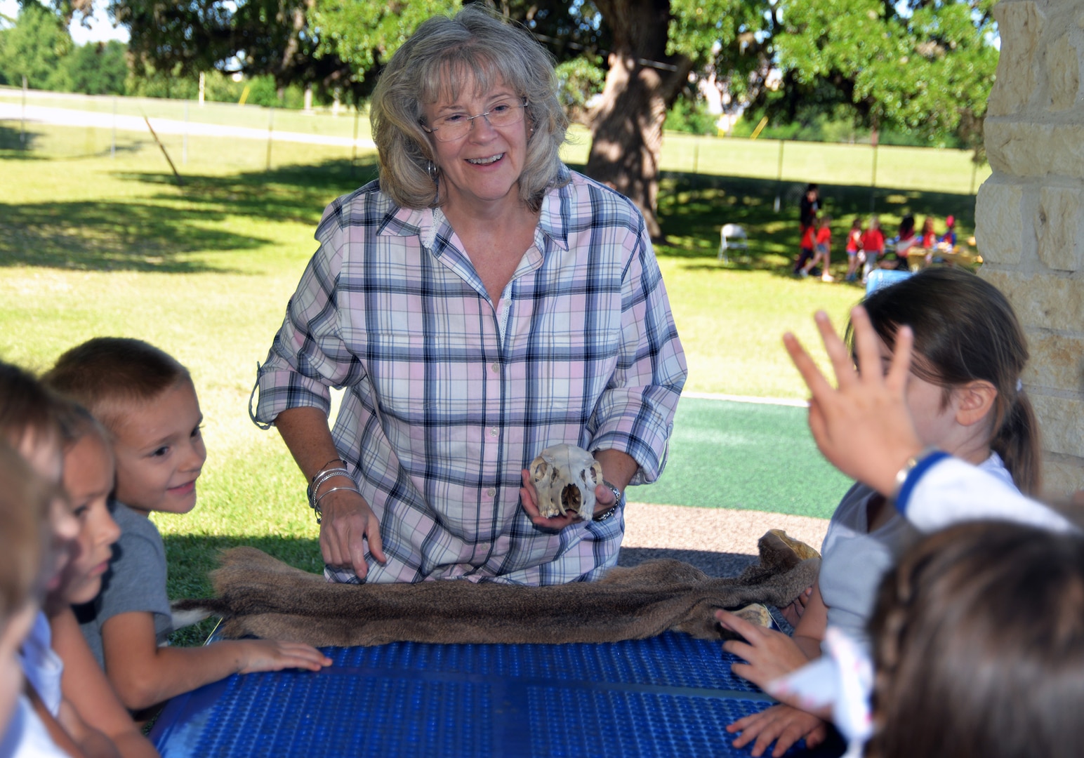 Ann Wood, U.S. Army Environmental Command West Division chief, shows a coyote skull and skin to students from Fort Sam Houston Elementary School during a nature field trip put on by the command at Salado Park, at Joint Base San Antonio-Fort Sam Houston, April 26.