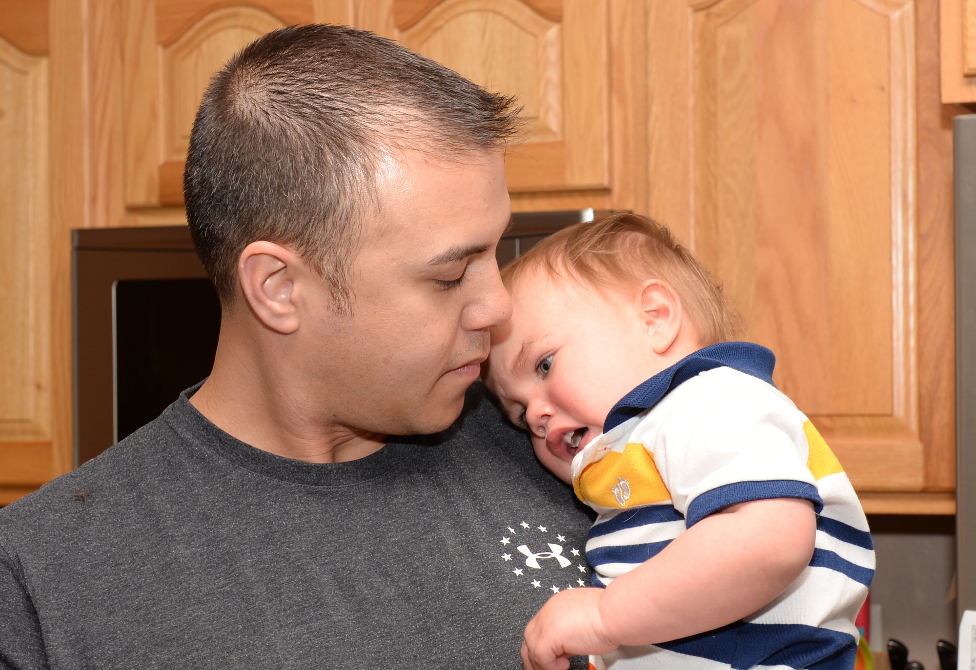Tech. Sgt. Brian Thomas, the 28th Civil Engineer Squadron noncommissioned officer in charge of power production, comforts his son at home in Box Elder, S.D., April 19, 2018. The family has been involved with supporting community youth programs and working in orphanages for more than 10 years. (U.S. Air Force photo by Airman 1st Class Nicolas Z. Erwin)