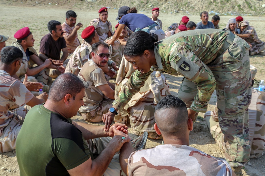 A soldier places her hand on another person's wrist.