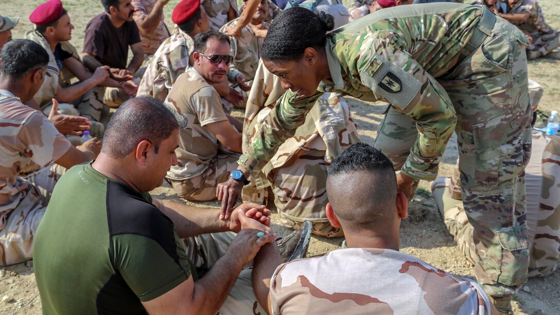 A soldier places her hand on another person's wrist.