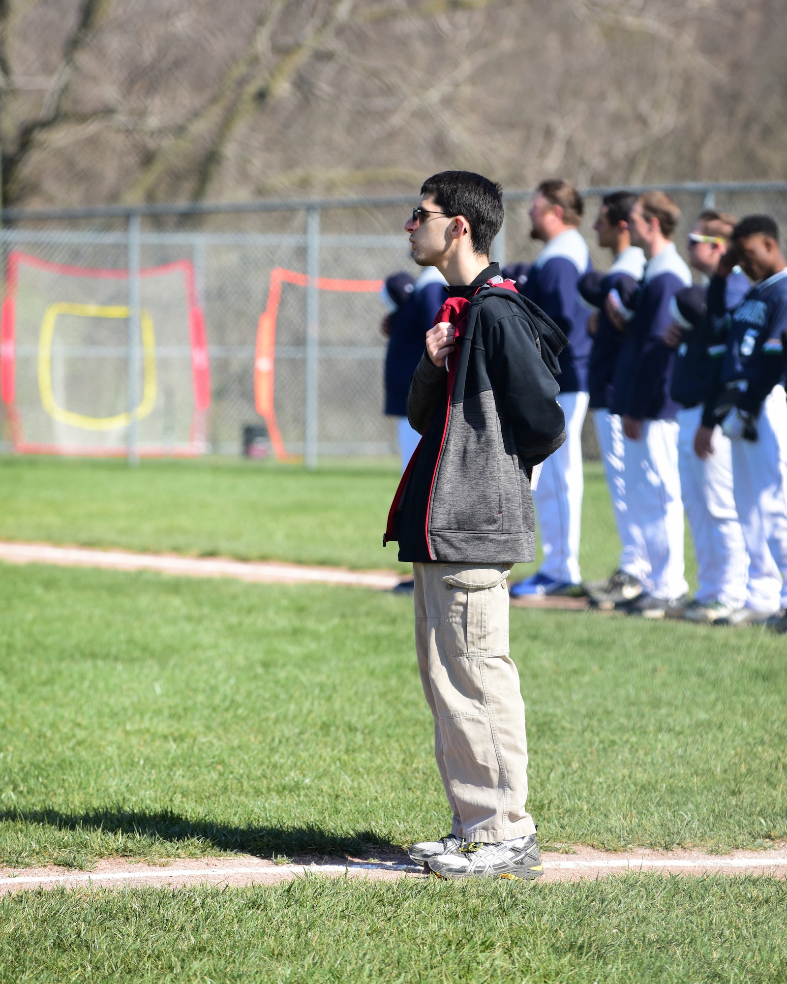 Andy Martins, a manager for the Warrensburg High School baseball team, stands with his hand over his heart during the playing of the national anthem before a game at West Park in Warrensburg, Mo., April 16, 2018. Growing up with autism, Andy has used sports as a way to strength his communication and socialization skills. (U.S. Air Force photo by Staff Sgt. Danielle Quilla)