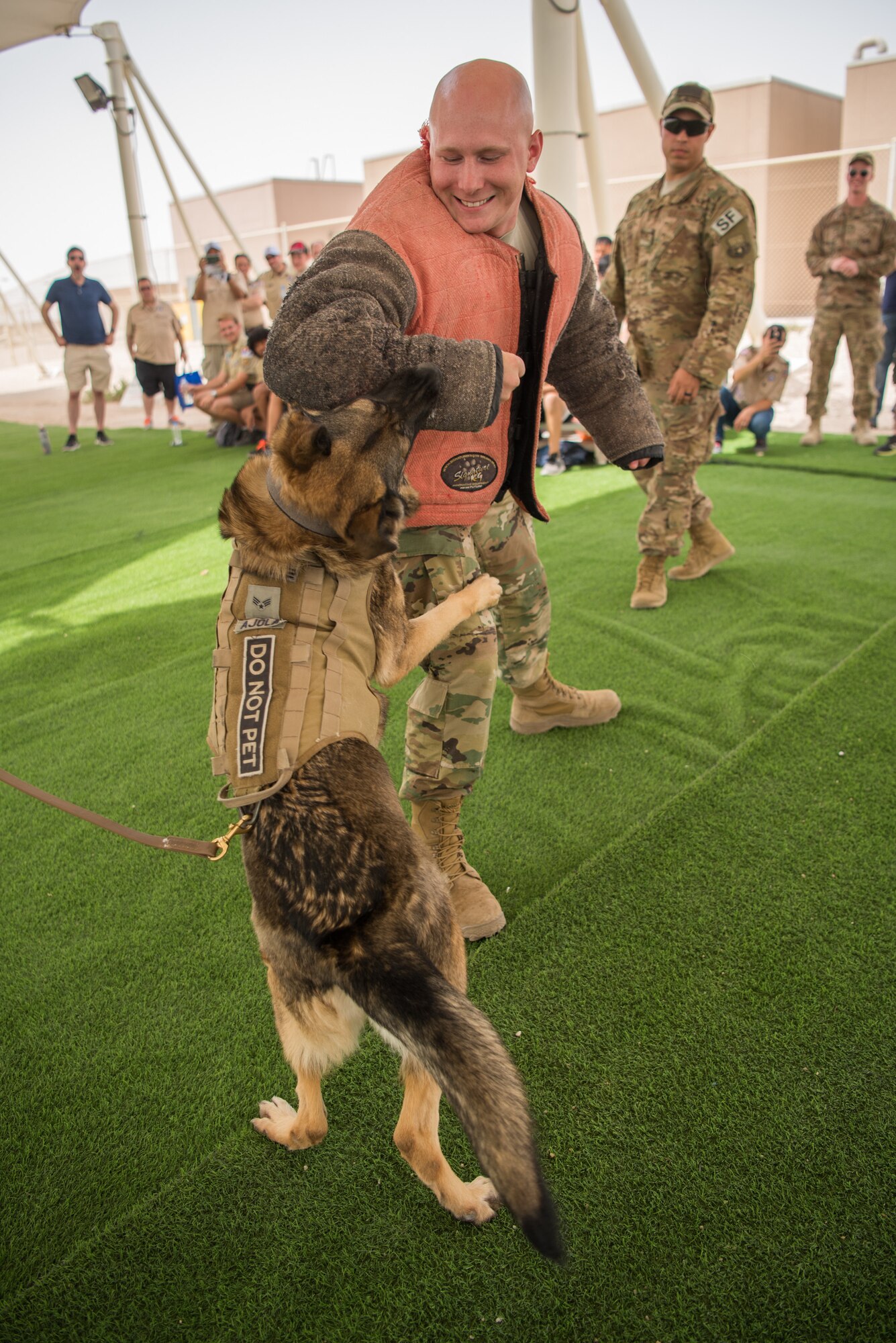 Boy Scouts watch as Staff Sgt. Lloyd Mickens, a 379th Expeditionary Civil Engineer Squadron force escort, demonstrates military working dog controlled aggression tactics with military working dog Ajola during a tour of Al Udeid Air Base, Qatar, April 21, 2018. The two-day visit, which was collaboratively coordinated by the 379th Air Expeditionary Wing and Qatar Emiri Air Force, provided the scouts a chance to earn merit badges, including the Aviation Merit Badge. (U.S. Air Force photo by Staff Sgt. Joshua Horton)