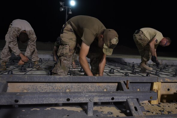 airman and marines work outside at night pouring concrete
