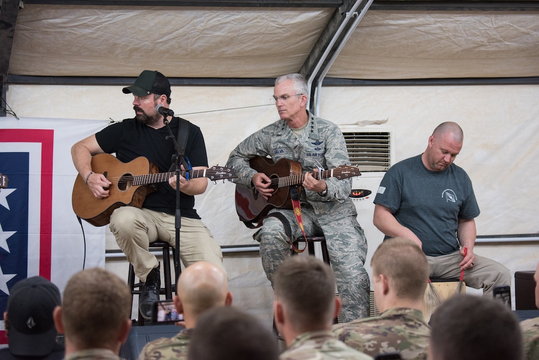 Air Force Gen. Paul J. Selva, vice chairman of the Joint Chiefs of Staff plays guitar on stage next to other entertainers.