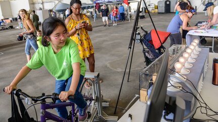 A young girl peddles a bike to power lights during an electrical demonstration at the Joint Base Charleston Air and Space Expo,  JB Charleston, S.C.  Apr 28, 2018.