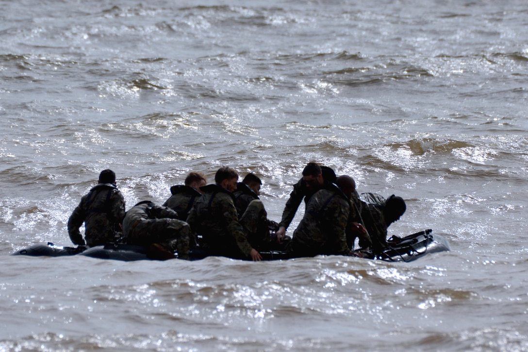 Soldiers climb aboard their combat raiding craft.