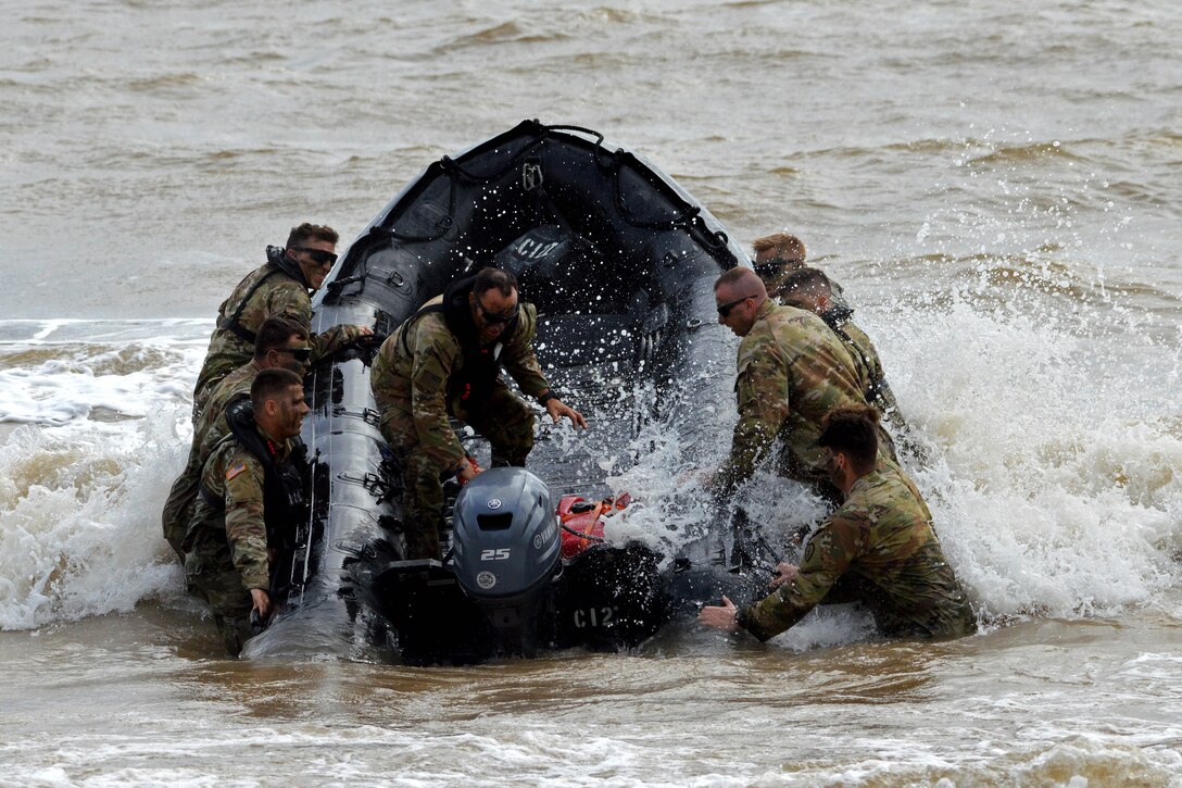 Soldiers fight large swells to get their watercraft out to sea.