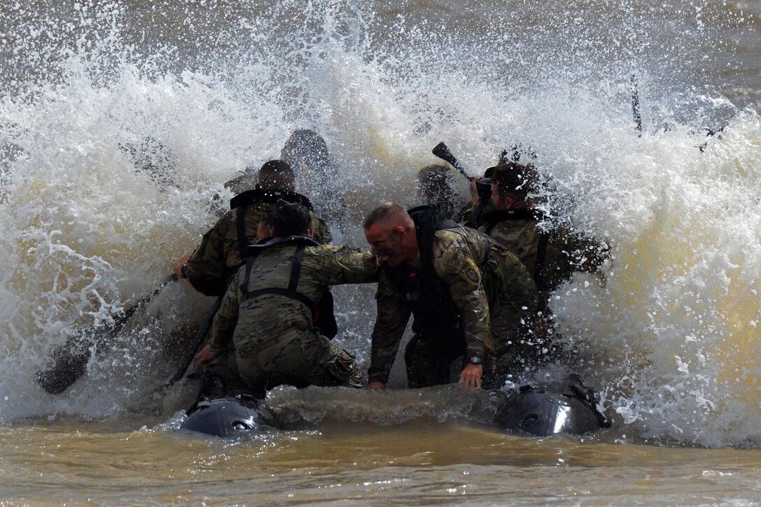 Waterborne soldiers get hit by a wave.