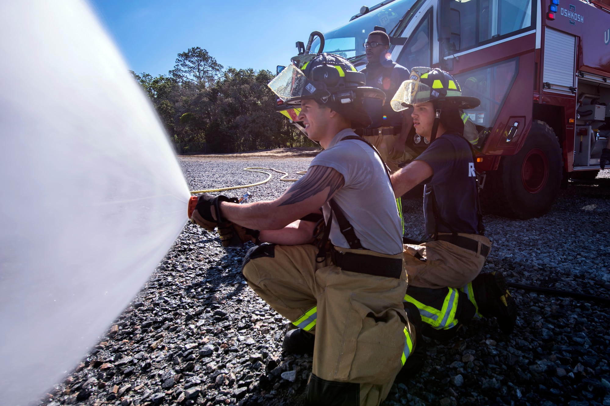 Firefighters from the 23d Civil Engineer Squadron (CES) spray a hose during live-fire training, April 24, 2018, at Moody Air Force Base, Ga. Firefighters from the 23d CES and Valdosta Fire Department participated in the training to gain more experience fighting aircraft fires and to work together as a cohesive team while still practicing proper and safe firefighting techniques. (U.S. Air Force photo by Airman Eugene Oliver)