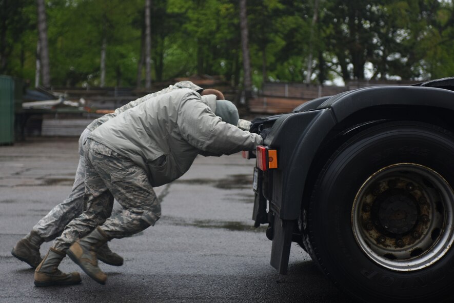 Airmen from the 48th Logistic Readiness Squadron push a tractor trailer during a ground transportation rodeo at Royal Air Force Lakenheath, England, April 27, 2018. The 48th LRS hosted a ground transportation rodeo where Airmen from the 100th and 48th LRS competed against each other in events to test their driving skills. (U.S. Air Force photo by Senior Airman Eli Chevalier)