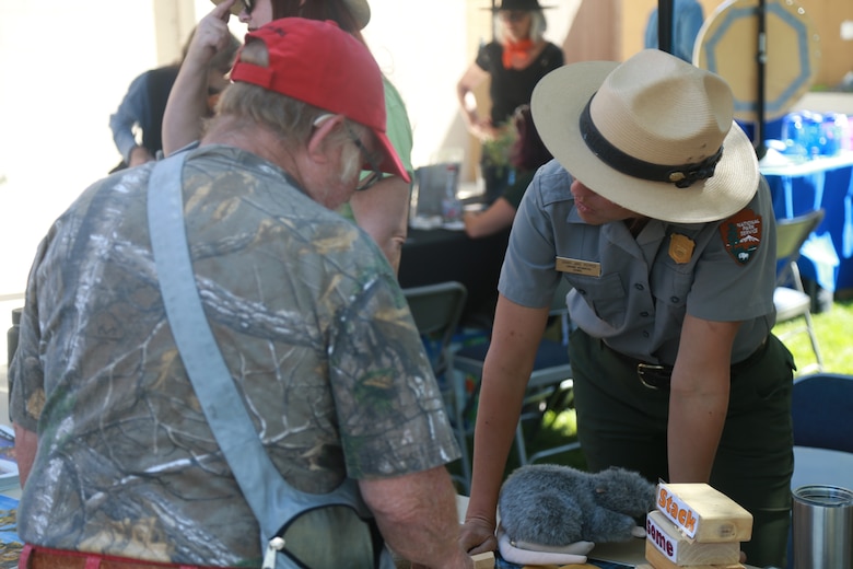 A ranger with the National Parks Service speaks to a local community member during the Earth Day Festival in Yucca Valley, Calif., April 21, 2018. The festival was held by the Hi-Desert Nature Museum to raise environmental consciousness and educate the public on wildlife conservation and resource management. (U.S. Marine Corps photo by Lance Cpl. Preston L. Morris)