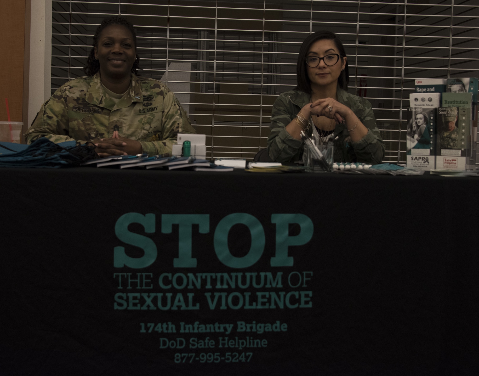 Sgt. 1st Class Pallas Cryer-Harris, Headquarters and Headquarters Command Brigade sexual assault response coordinator, and a team member with the 174th Infantry Brigade Sexual Assault Prevention and Response team sit at a booth during the Health and Wellness Fair at The Exchange on Joint Base McGuire-Dix-Lakehurst, N.J., April 18, 2018. The 174th IN BDE was one of many information booths to help service members and their families become more knowledgeable about the helping agencies available. (U.S. Air Force photo by Airman Ariel Owings)