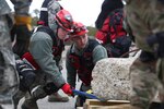 Senior Airman Jesse D. Hyam and Staff Sgt. Alexander J. Barnhart, medical search and extraction team members assigned to the 157th Medical Group, N.H. Air National Guard, work to lift debris during a simulated exercise on April 11, 2018 at Joint Base Cape Cod, Mass. Hyam and Barnhart participated in a weeklong regional deployment readiness exercise as members of the N.H. CBRNE Enhanced Response Force Package team.