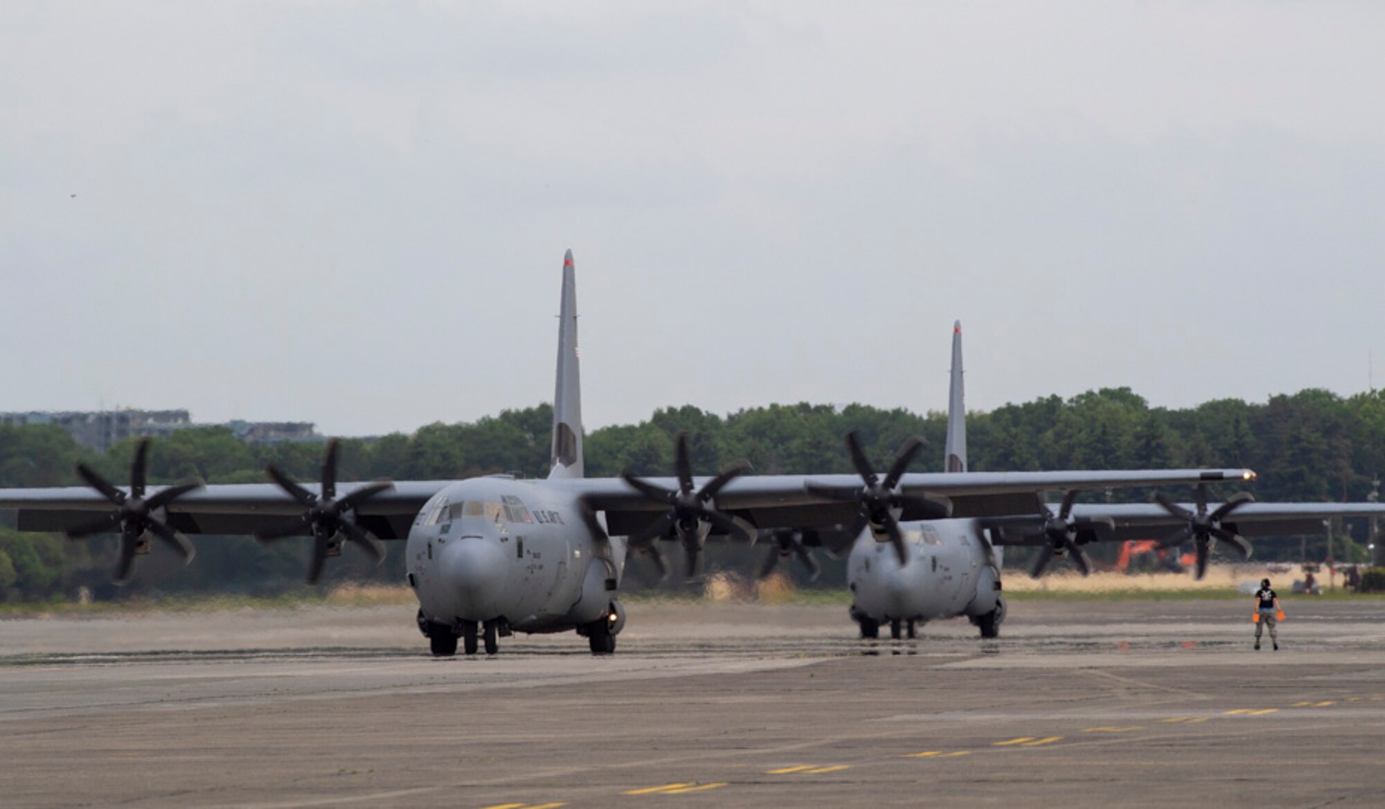 A crew chief assigned to the 374th Aircraft Maintenance Squadron marshals a C-130J Super Hercules at Yokota Air Base