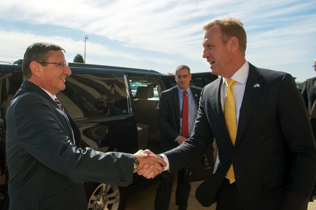 The deputy defense secretary shakes hands with another person.