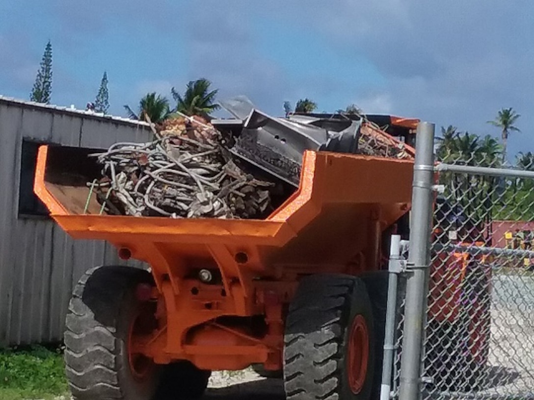 Truckers begin transporting scrap material to the first of two barges for transport off the island.