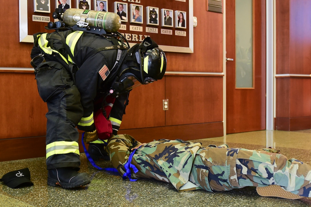 A firefighter drags a victim from a simulated explosion.