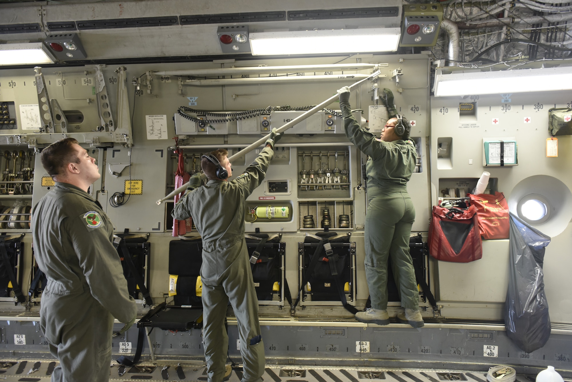 U.S. Air Force Capt. Aaron Rankin (middle) and Airman 1st Class Sylvia Bannister (right), members of the 156th Aeromedical Evacuation Squadron, prep a C-17 Globemaster III aircraft to transport aeromedical evacuation equipment from North Carolina Air National Guard Base, Charlotte Douglas International Airport, to Volk Field Air National Guard Base, Wisconsin, for a training exercise, July 9, 2018. (U.S. Air Force photo by Tech. Sgt. Nathan Clark)