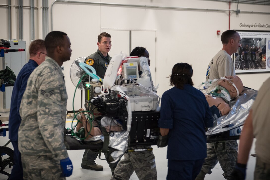 Staff Sgt. Travis Largent, Critical Care Air Transport Team initial course instructor, observes as students load critical patient-manikins in the back of a simulator fuselage. Largent and other instructors teach students how to package all the equipment needed for the patient to sustain treatment while being transported. (U.S. Air Force photo by Richard  Eldridge)