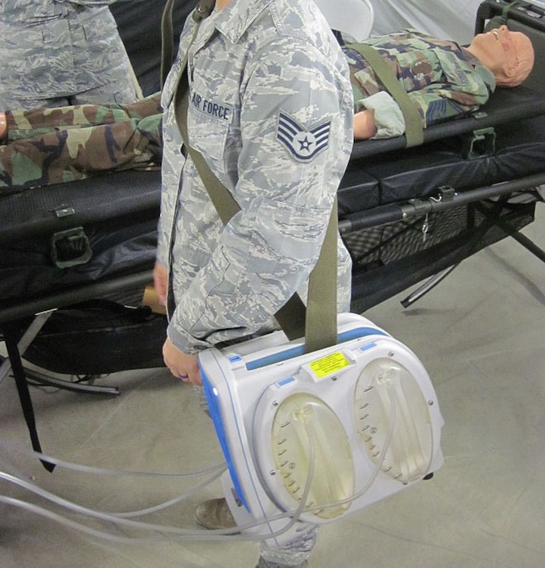 An Airman straps on the multi-channel wound vacuum system during training at the 59th Medical Wing, San Antonio, Texas, Nov. 30, 2016. The multi-channel wound vacuum system, which is used to help promote wound healing on critical patients, is able to replace four single-channel systems. This smaller, more transportable device makes it easier for aeromedical evacuation crews to deliver en route wound care to patients with multiple wounds on the back of an aircraft where space is limited. The Air Force Medical Evaluation Support Activity (AFMESA) team was involved in the development and testing of the multi-channel wound vacuum system, ensuring the device could perform in the operational environment.