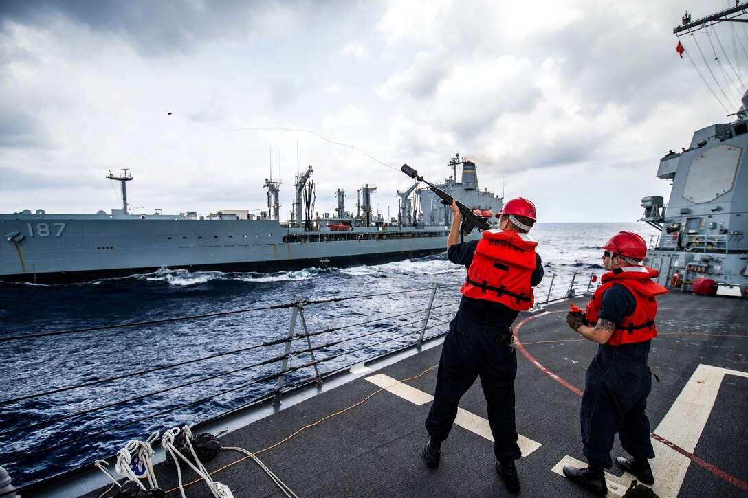 A sailor fires a shot line during a replenishment-at-sea.
