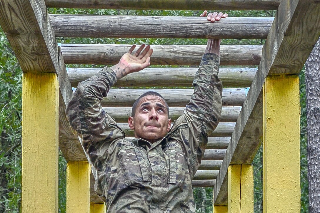 A soldier uses monkey bars.