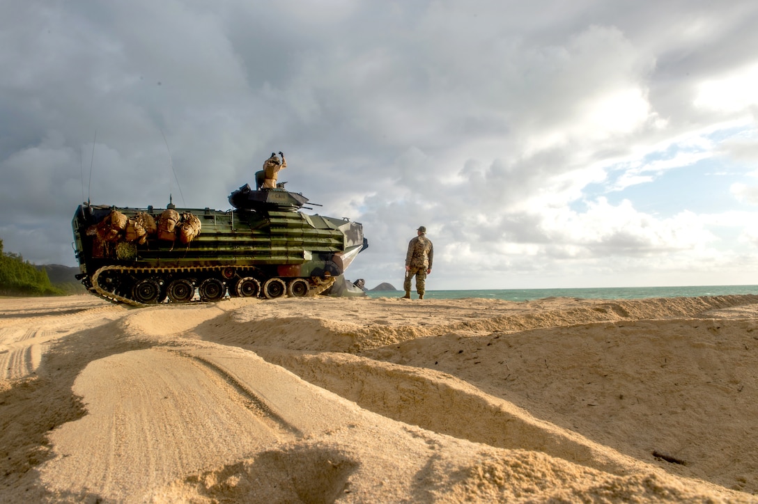 Marines stand near and on an amphibious vehicle.