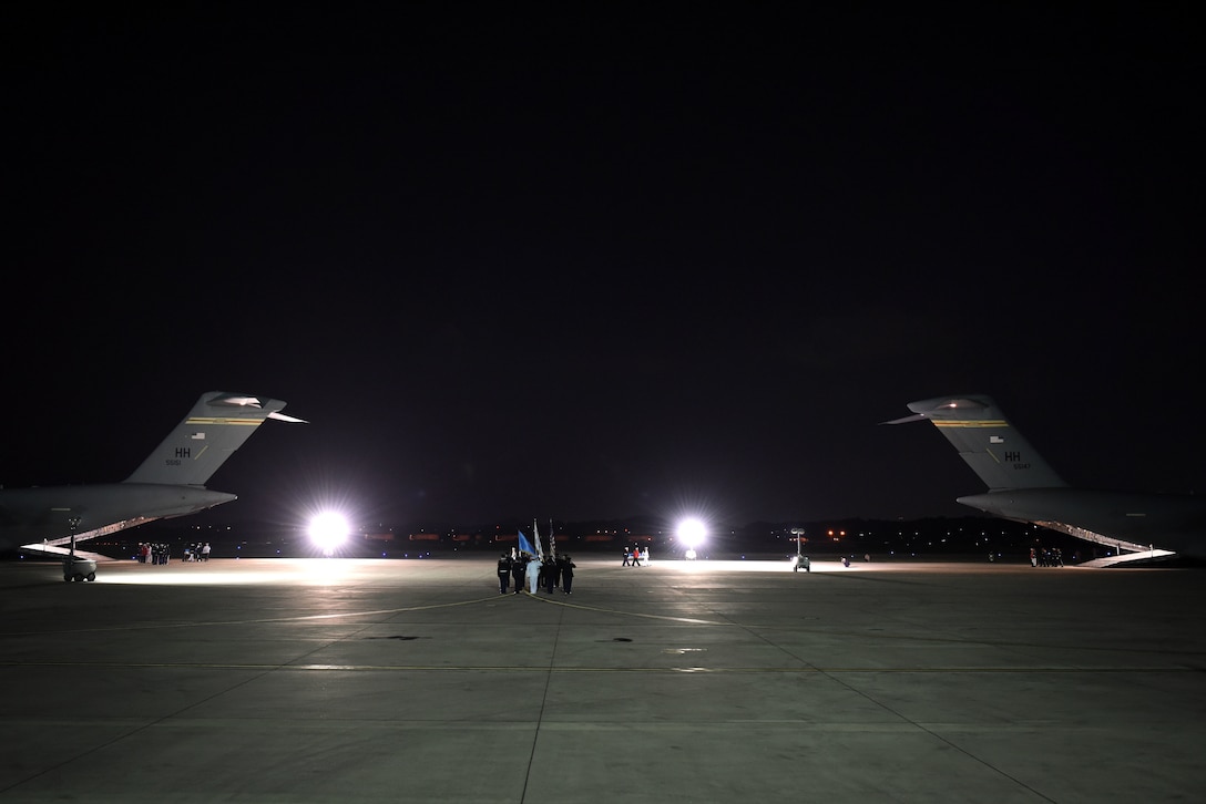 United Nations Command Honor Guard members move cases of remains from one aircraft to another.