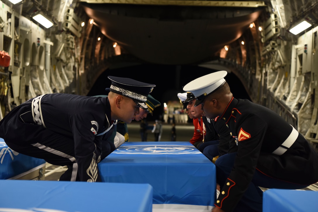 United Nations Command Honor Guard members move cases of remains from one aircraft to another.