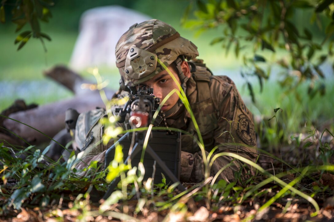 Airman 1st Class Luis Perez, 822d Base Defense Squadron fireteam member, scans the simulated forward operating base perimeter with an M249 light machine gun, July 25, 2018, at Moody Air Force Base, Ga. The ‘Safeside’ defenders evaluated their base defense tactics and procedures while performing patrols, tactical combat casualty care and countering improvised explosive devices for a mission readiness exercise. After successfully completing these events, the defenders are eligible to earn their Global Response Force status, which certifies the unit to deploy worldwide. (U.S. Air Force photo by Airman 1st Class Eugene Oliver)