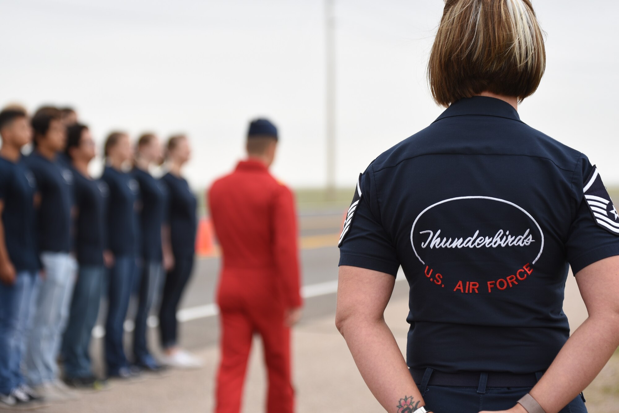 Master Sgt. Christine Powers, Air Demonstration Squadron Public Affairs, stands by as Air Force recruits swear into the Delayed Entry Program during the Thunderbirds airshow July 25, 2018, in Cheyenne, Wyo. The airshow provides a chance for the local community and worldwide visitors of CFD to see the U.S. Air Force in action over the skies of Cheyenne. (U.S. Air Force photo by Airman 1st Class Abbigayle Wagner)