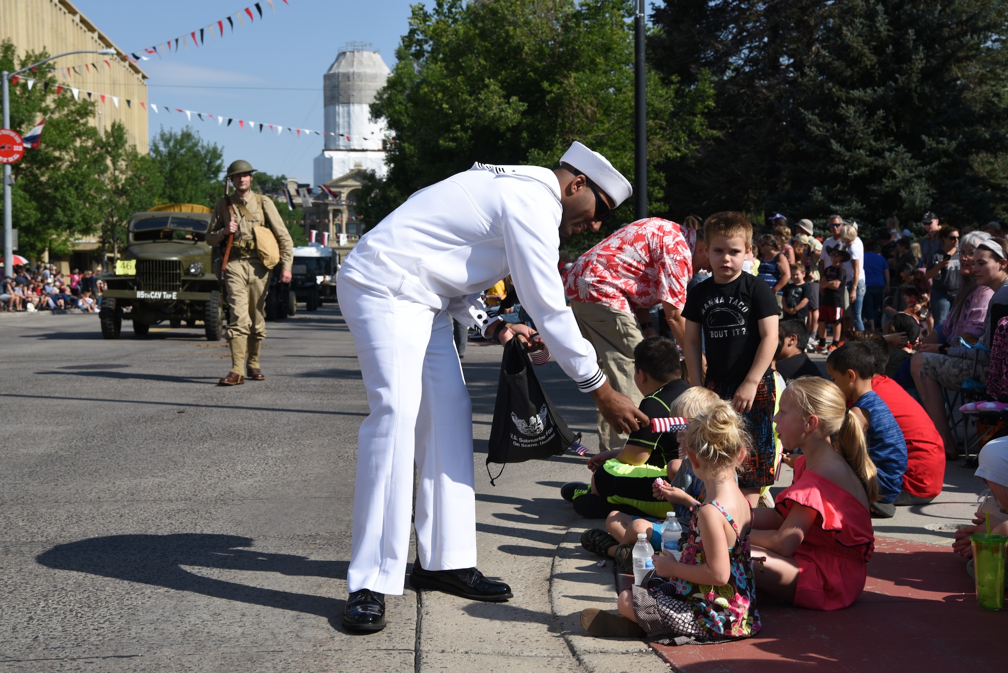 A U.S. Navy Sailor hands out American flags during the Cheyenne Frontier Days Grand Parade July 21, 2018, Cheyenne, Wyo. F.E. Warren Air Force Base’s involvement during CFD provides an opportunity to showcase the everlasting relationship between the base and the local community. (U.S. Air Force photo by Airman 1st Class Abbigayle Wagner)