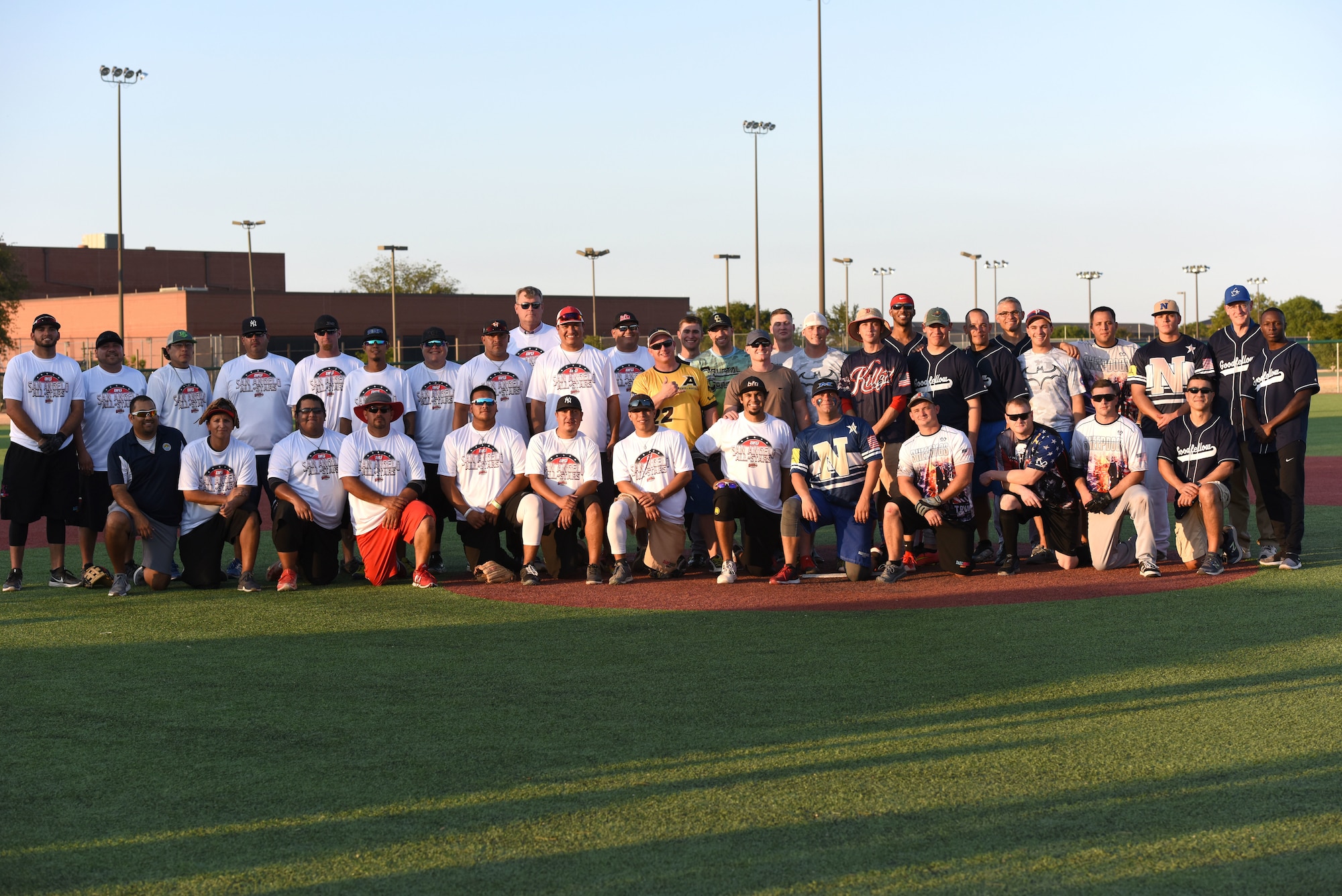Goodfellow and San Angelo team members stand together after the Stars and Strikes softball game held at the Matthis Fitness Center softball field on Goodfellow Air Force Base, Texas, July 31, 2018. Friends and family members were able to attend to support their players during the game between the base and the city’s team. (U.S. Air Force photo by Airman 1st Class Seraiah Hines/Released)