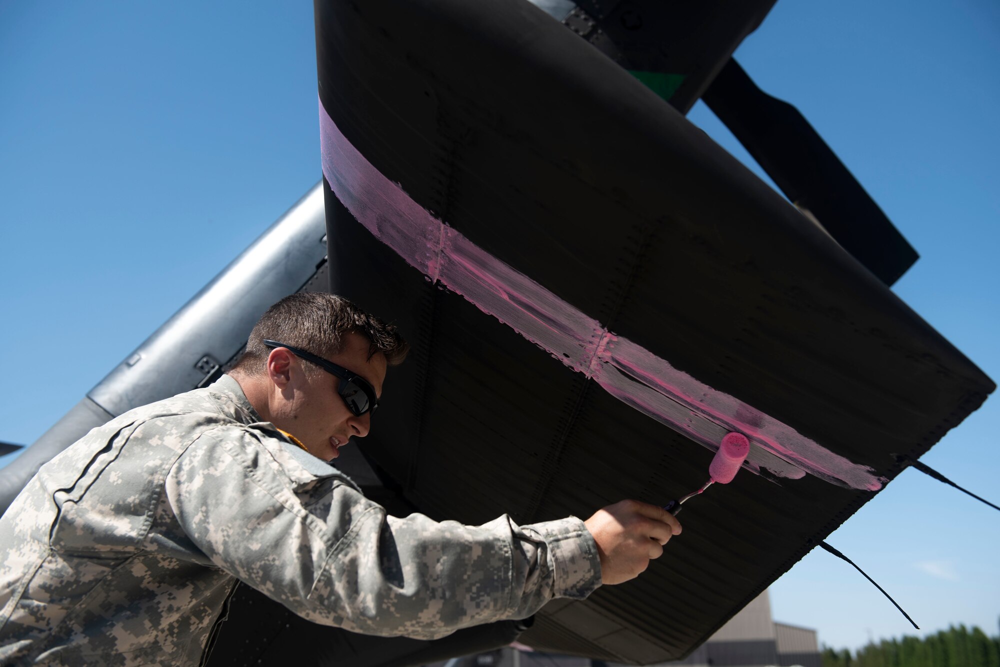 U.S. Army SGT. William Hust, 96th Aviation Troop Command crew chief assigned to Joint Base Lewis-McChord, paints the tail of a Sikorsky UH-60 Blackhawk helicopter at Fairchild Air Force Base, Washington, Aug. 1, 2018. Two Washington National Guard Blackhawks were staged at Fairchild to fight the wildfire dubbed “The Sheep Creek Fire.” By painting the helicopters with pink-colored paint, the helicopters are more visible to ground crews they’re supporting. (U.S. Air Force photo/Airman 1st Class Whitney Laine)