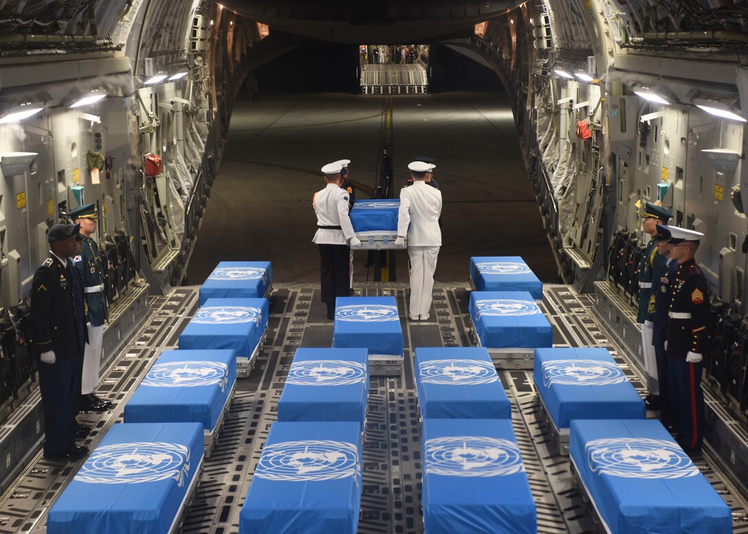 United Nations Command Honor Guard members move cases of remains from one aircraft to another.