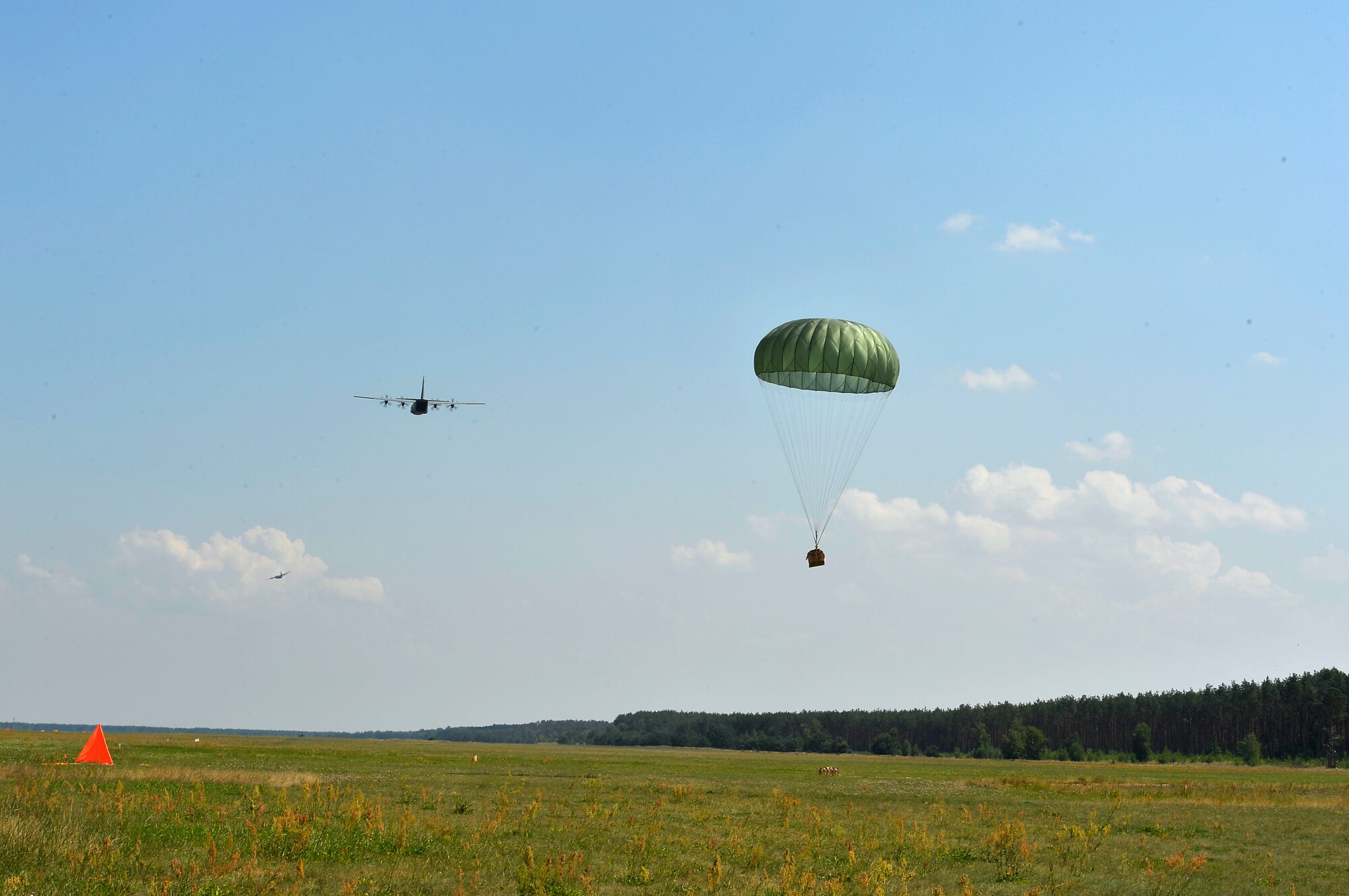 A U.S. Air Force C-130J Super Hercules assigned to the 86th Airlift Wing airdrops a bundle onto a field at Powidz Air Base, Poland, July 31, 2018, during Aviation Detachment Rotation 18-4. The exercise is a bilateral training event between U.S. and Polish troops which involves rigorous flight training and tactical airlift scenarios. (U.S. Air Force photo by Senior Airman Joshua Magbanua)