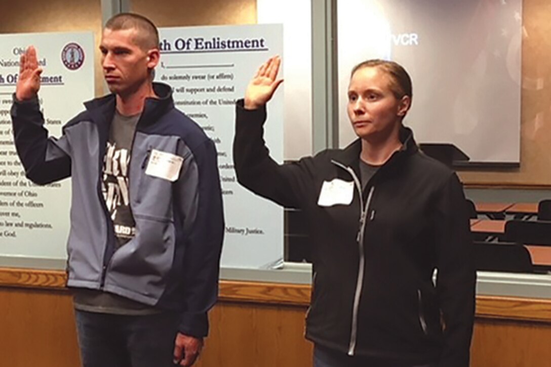 A man and a woman take the oath of enlistment in the military.