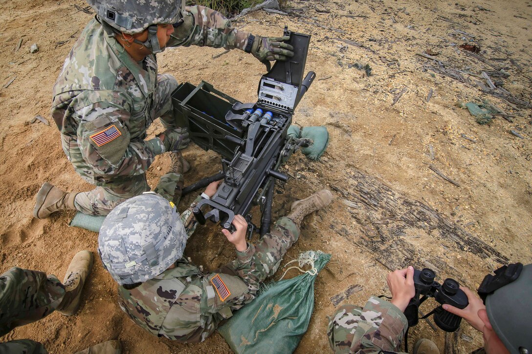 Soldiers clear unused 40 mm M385 practice grenades from a MK 19 grenade launcher.
