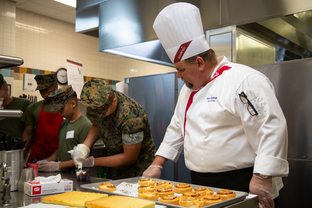 Ross Ragonese, executive chef, Sodexo, supervises a Marine making a yogurt parfait at Mess Hall 128, Marine Corps Base Camp Lejeune, July 11. The training teaches Marine food service specialists methods to improve the basic services they provide involving baking, roasting, recipe use, cold food preparation and grilling. (U.S. Marine Corps photo by Lance Cpl. Ashley Gomez)