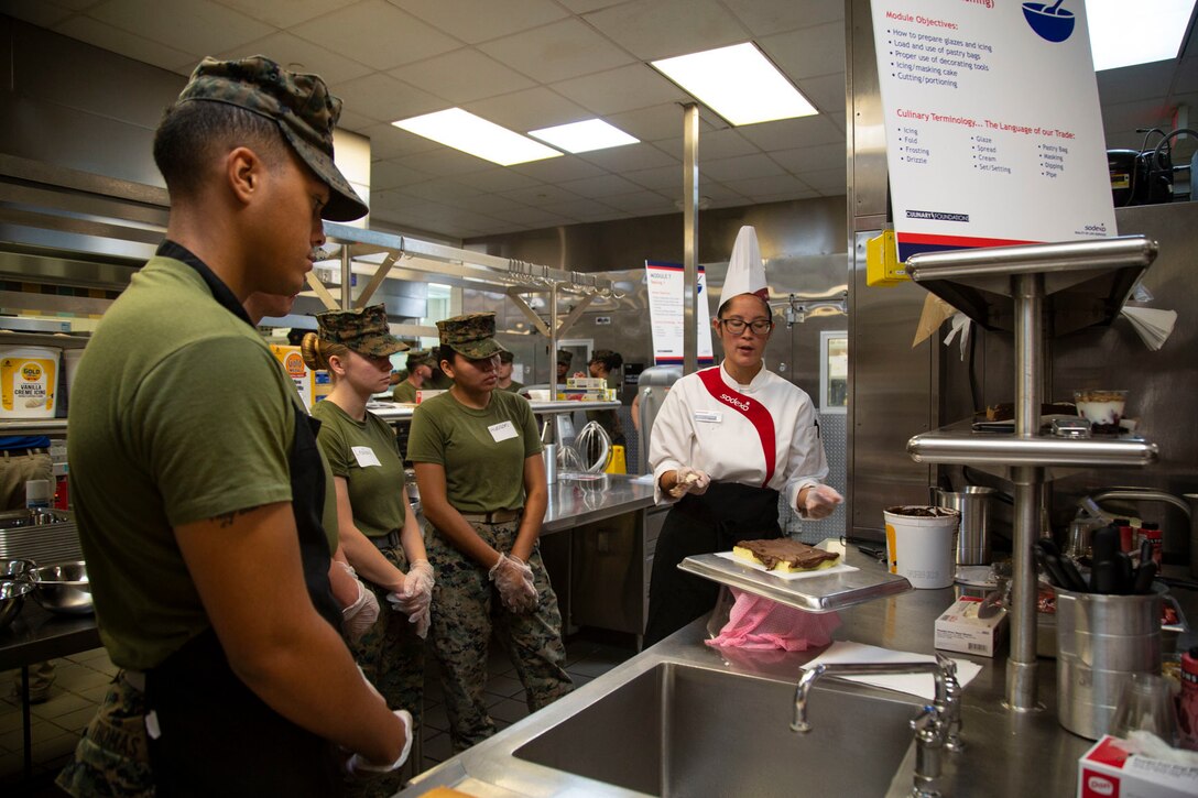 Evangeline Garcia, executive chef, Sodexo, demonstrates cake frosting to Marines at Mess Hall 128, Marine Corps Base Camp Lejeune, July 11. The training teaches Marine food service specialists methods to improve the basic services they provide involving baking, roasting, recipe use, cold food preparation and grilling. (U.S. Marine Corps photo by Lance Cpl. Ashley Gomez)